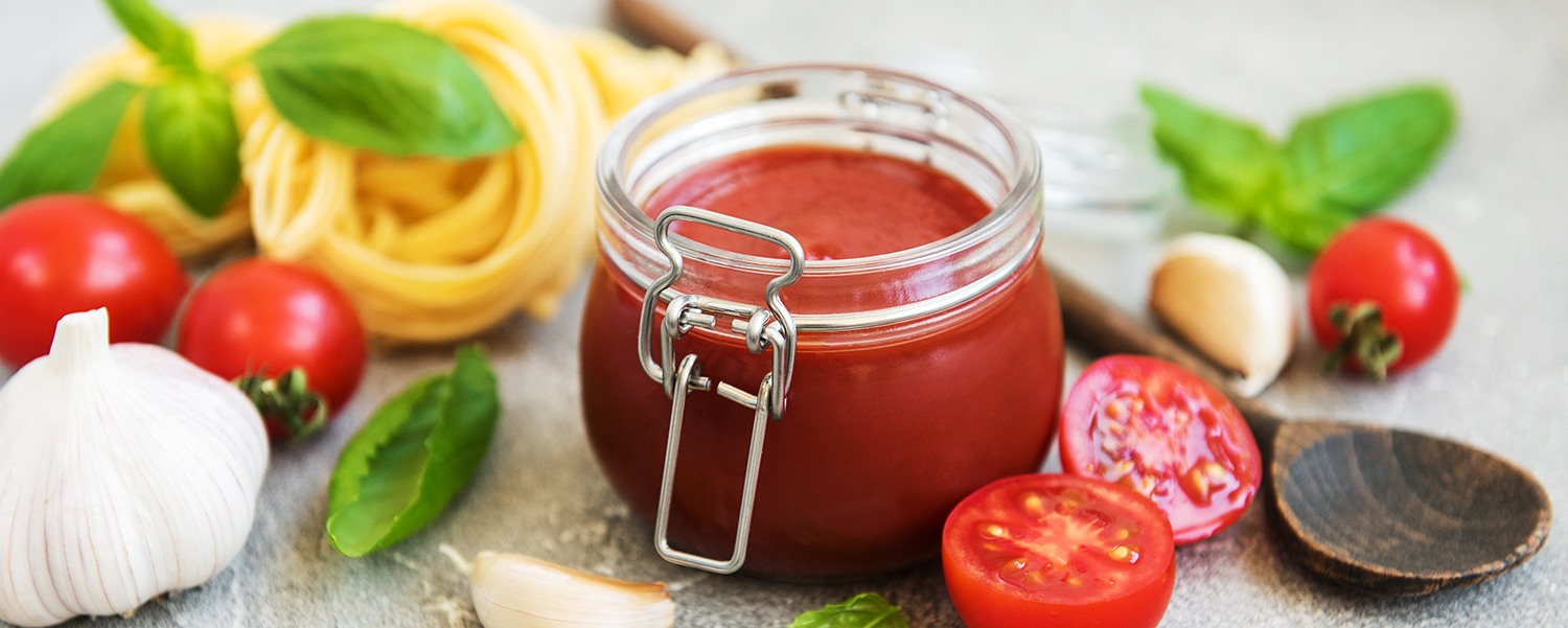 Jar with tomato sauce and ingredients on a stone background