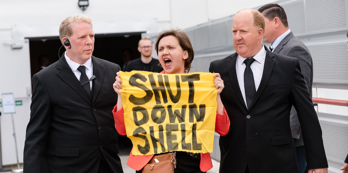 A protestor carrying a sign saying Shut Down Shell