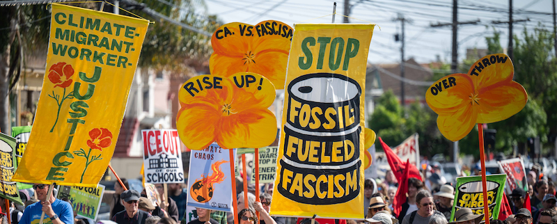 People holding colorful signs saying "Stop fossil fueled fascism"