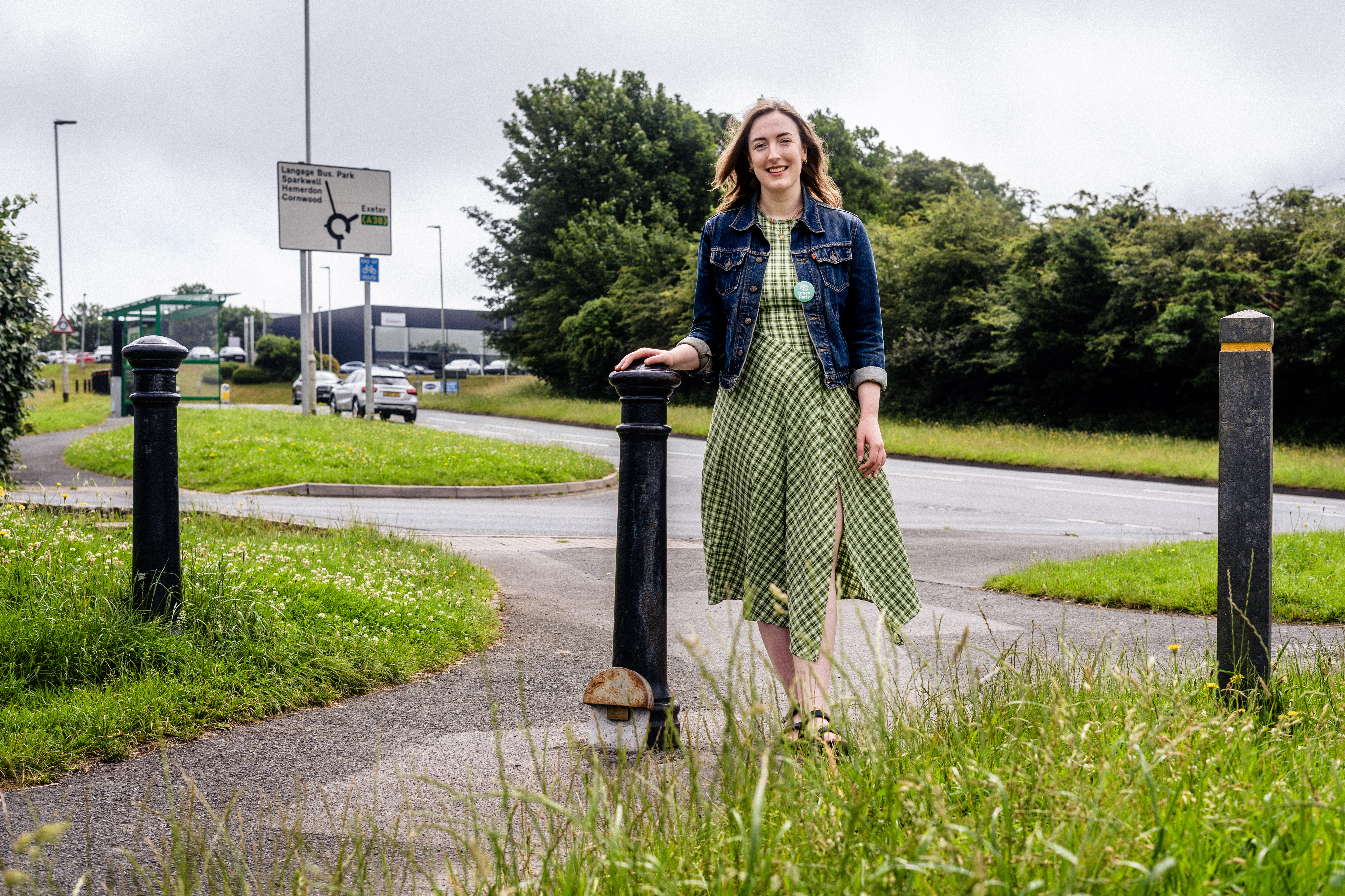 Councillor Lauren McLay is wearing a green dress. She is smiling and had her hand placed on a park bollard
