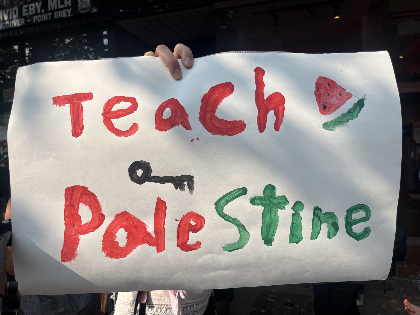 Hand painted banner that reads ‘Teach Palestine’ with a picture of a key underneath