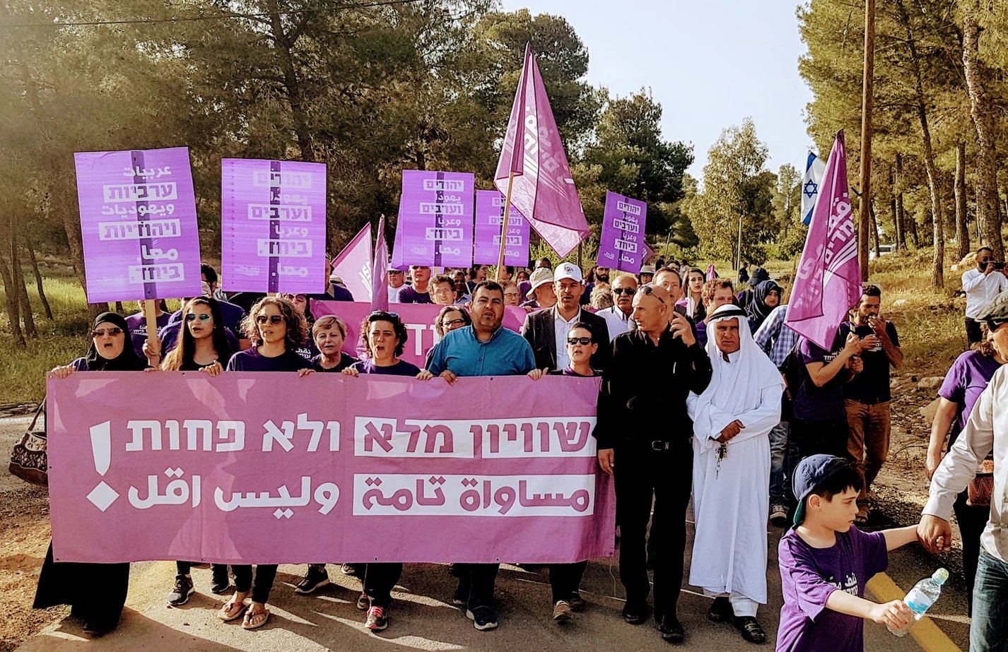 Israeli Jewish and Palestinian protests marching together with a banner that reads, in Arabic and Hebrew, "Full Equality and Nothing Less"