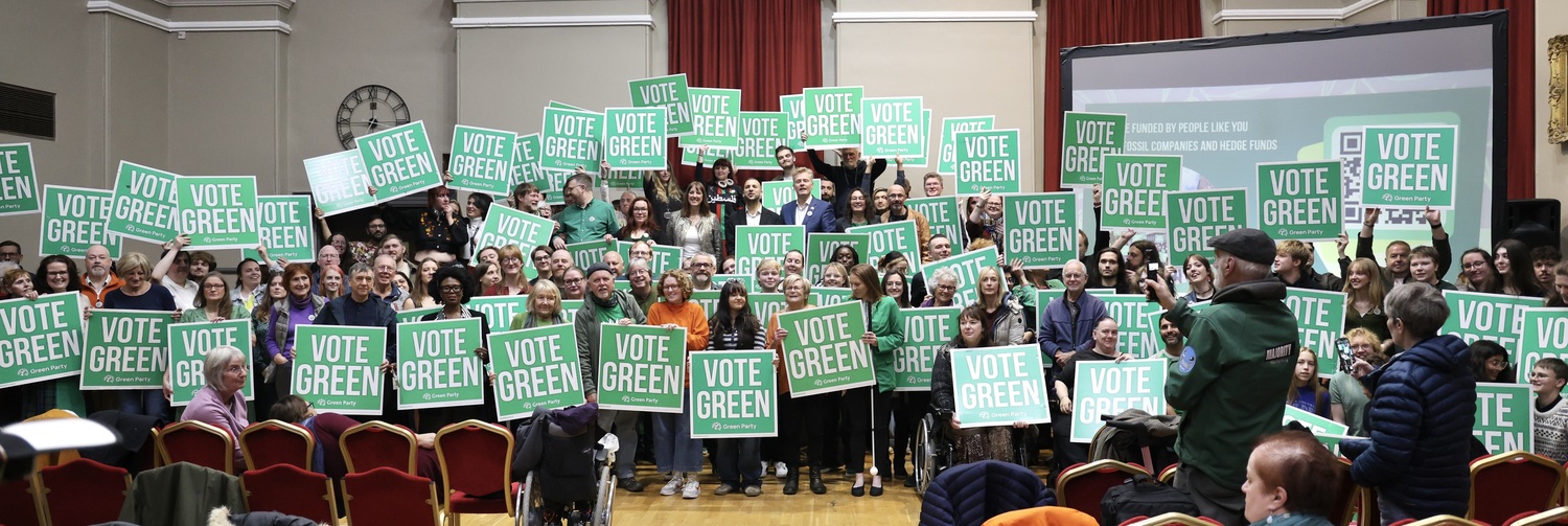 Large group of people holding Vote Green signs