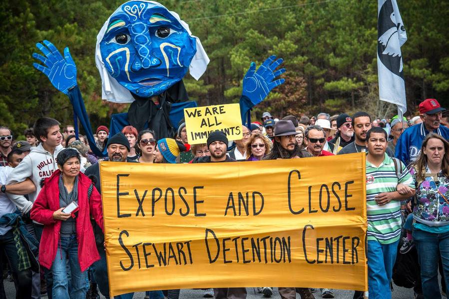 Photo of activists holding a banner that says "Expose and Close Stewart Detention Center".