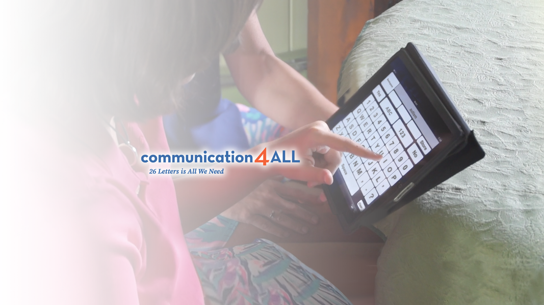 Elizabeth types "autism" on an iPad with Ginnie seated at a table, with the Communication 4 ALL logo and "26 Letters is All We Need" overlaid."