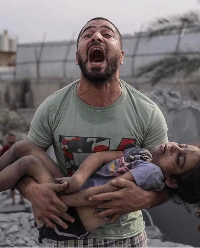 A Gazan father holds his daughter, murdered by Israeli colonial forces, as he carries her out of the rubble of a building. October 9, 2023.
