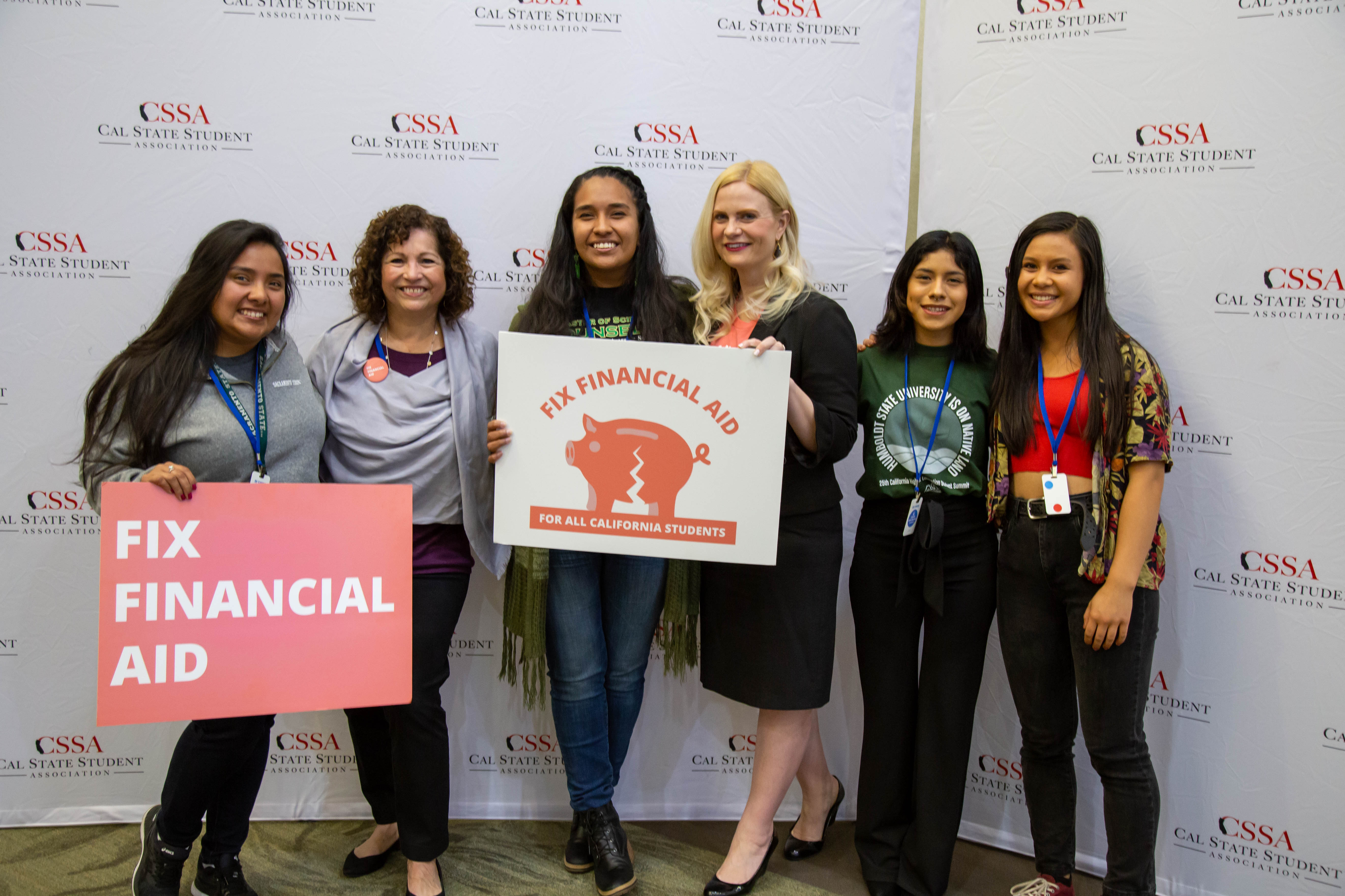 A group of students wearing Fix Financial Aid Coalition shirts are shown. The Coalition logo includes an image of a pig. The students are holding a poster that says "Fix Financial Aid". 
