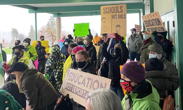 Protest outside Lord Tweedsmuir Elementary. Signs say "Education not deportation", "schools not jails" and "CBSA ruins Christmas"