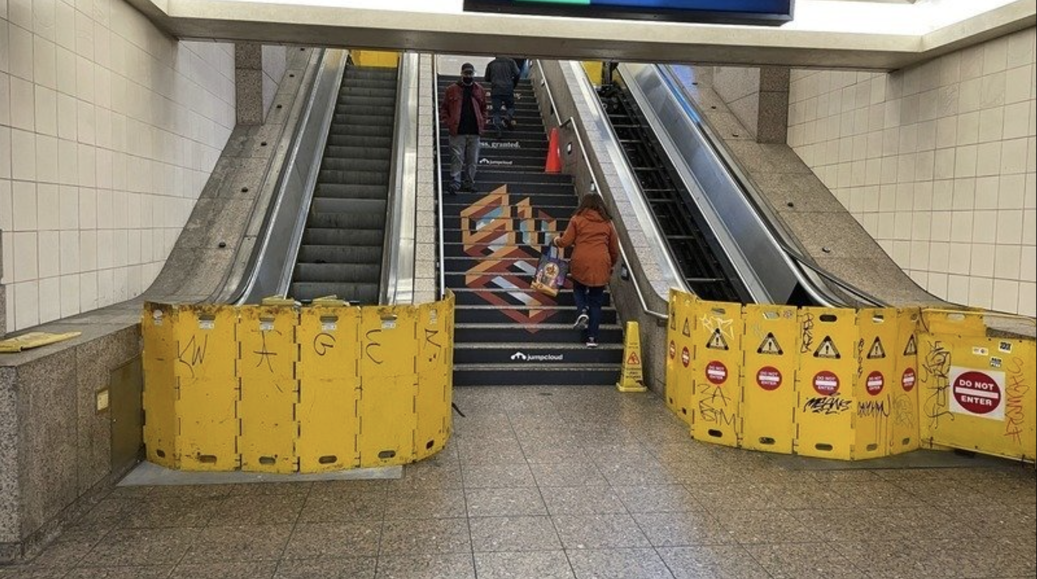 Escalators out of service at Westlake Station while people hike the stairs.