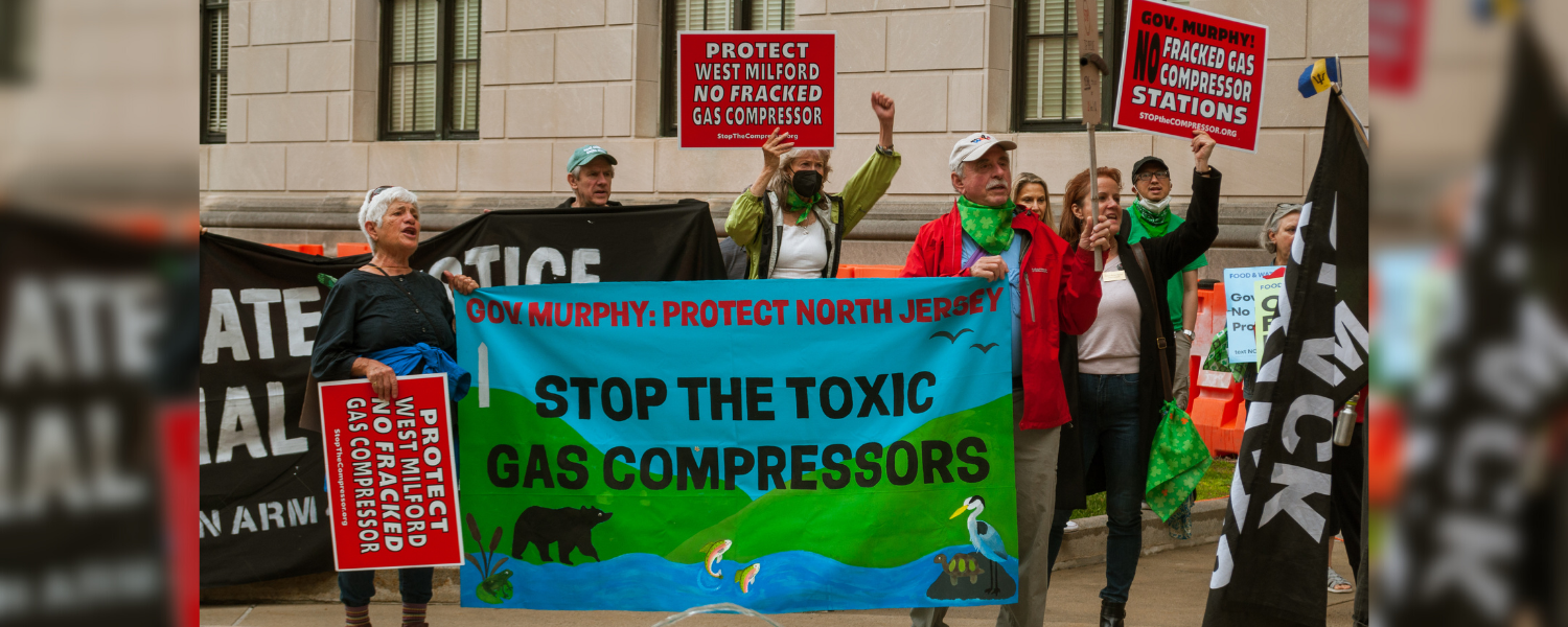Activists stand at a rally with a banner that reads: Gov. Murphy, Protect North Jersey, Stop the Toxic Gas Compressors
