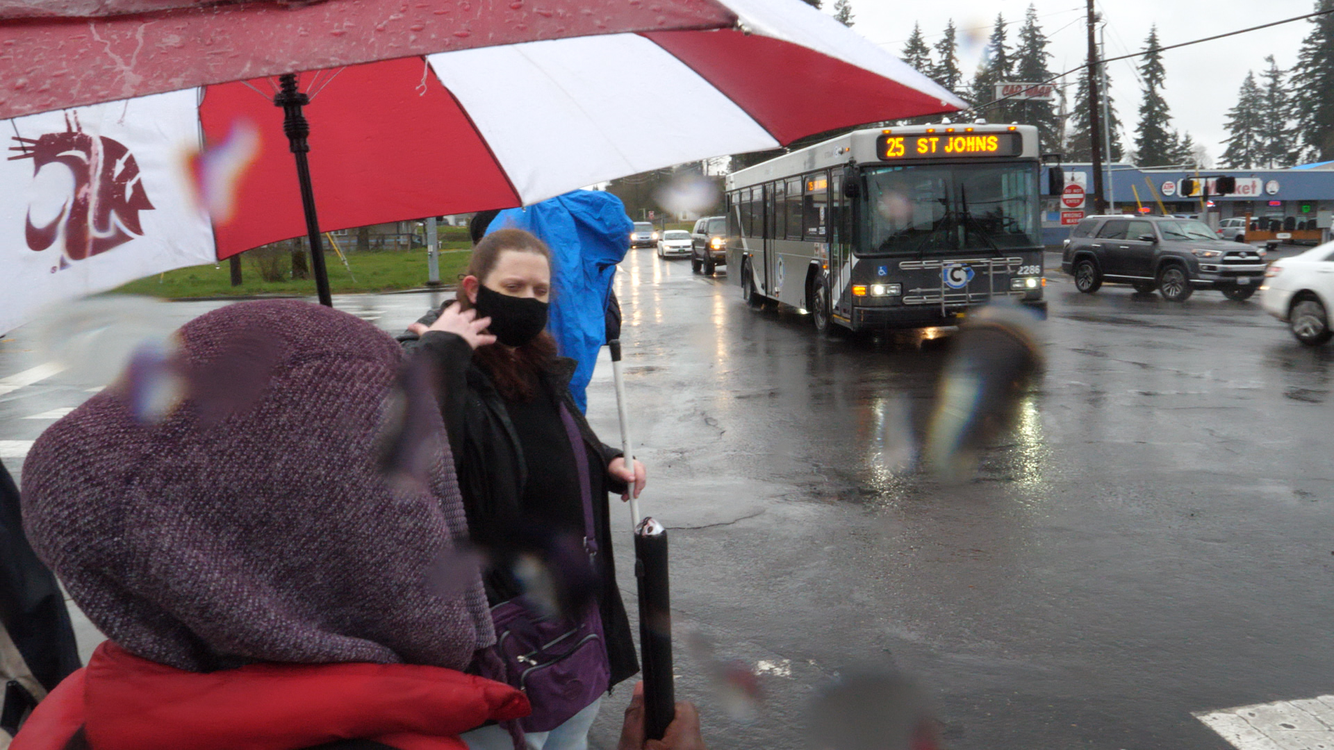 Rainy bus stop with people waiting