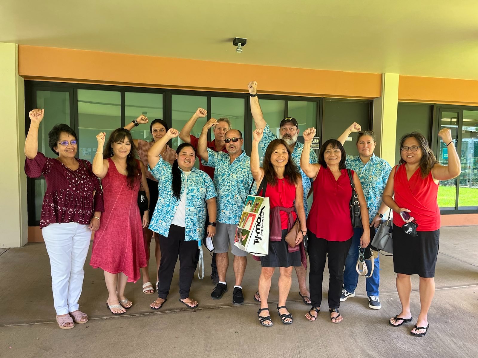 Members of the Maui News, who are fighting for a fair contract, stand with raised fists in solidarity.