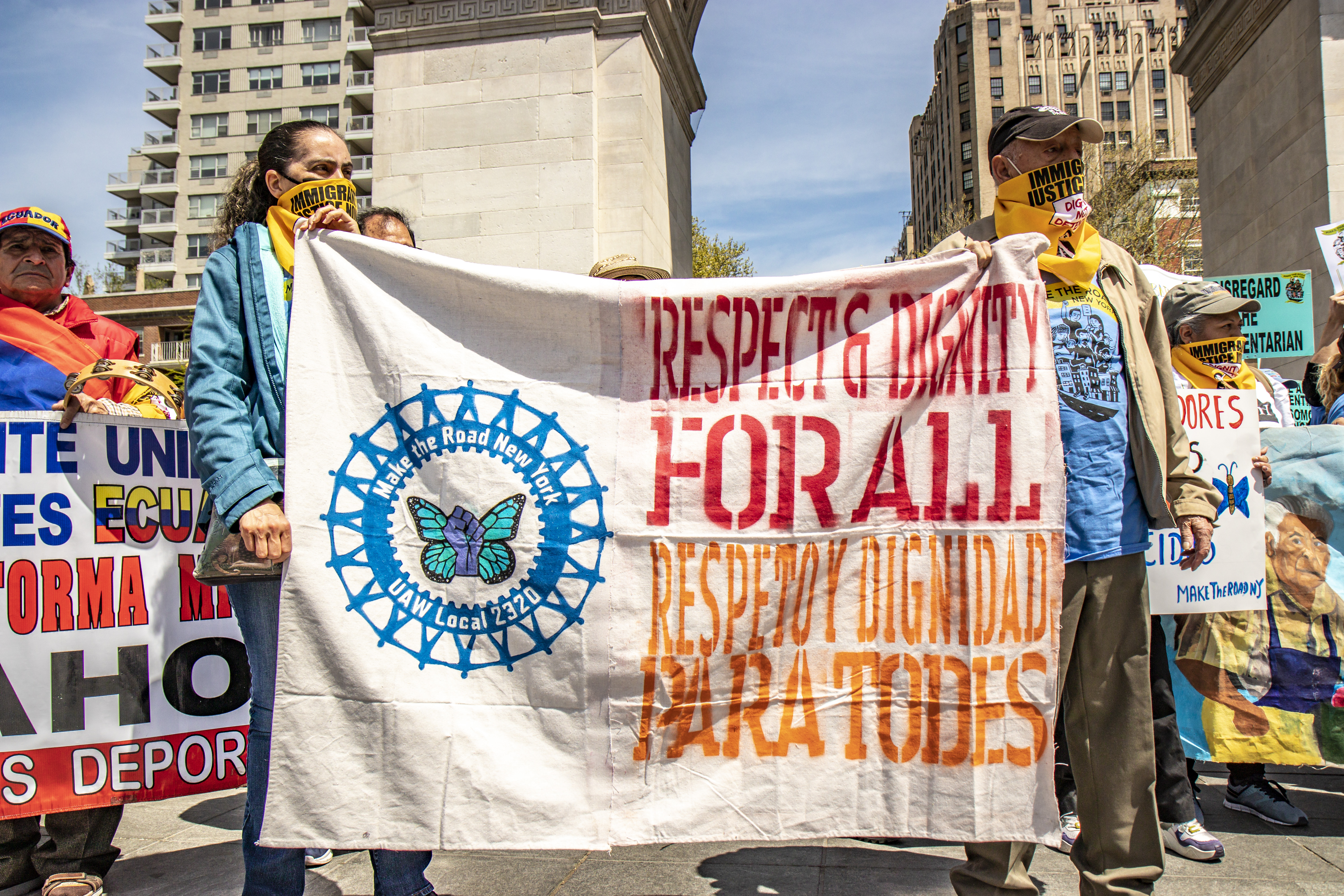 Immigrant justice advocates gather in Washington Square Park, holding a banner reading: Respect & Dignity For All / Respeto y dignidad para todos