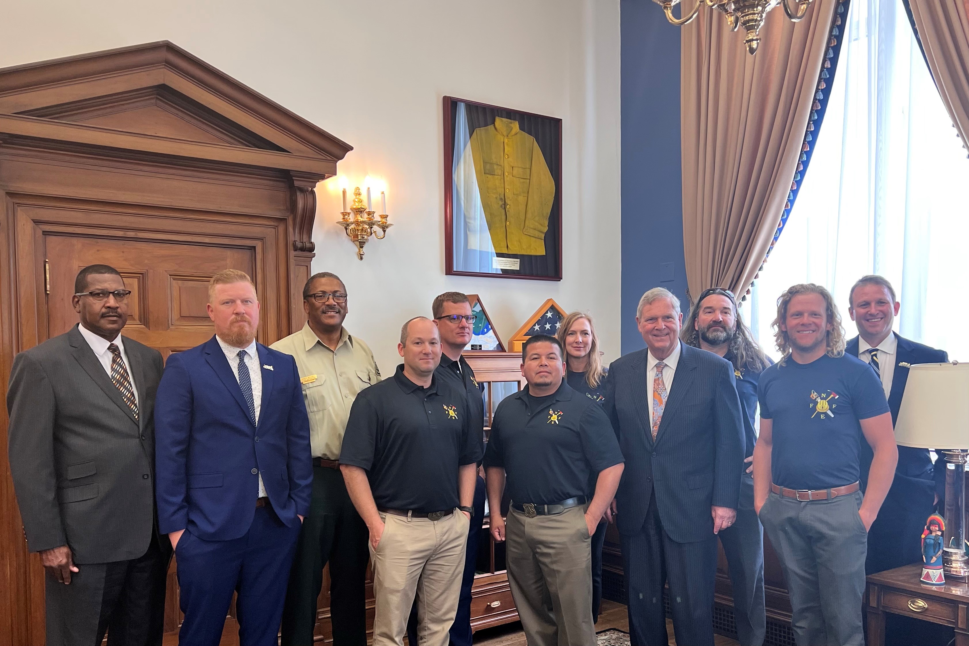 NFFE Wildland Firefighters in front of uniform worn by Tim Hart 