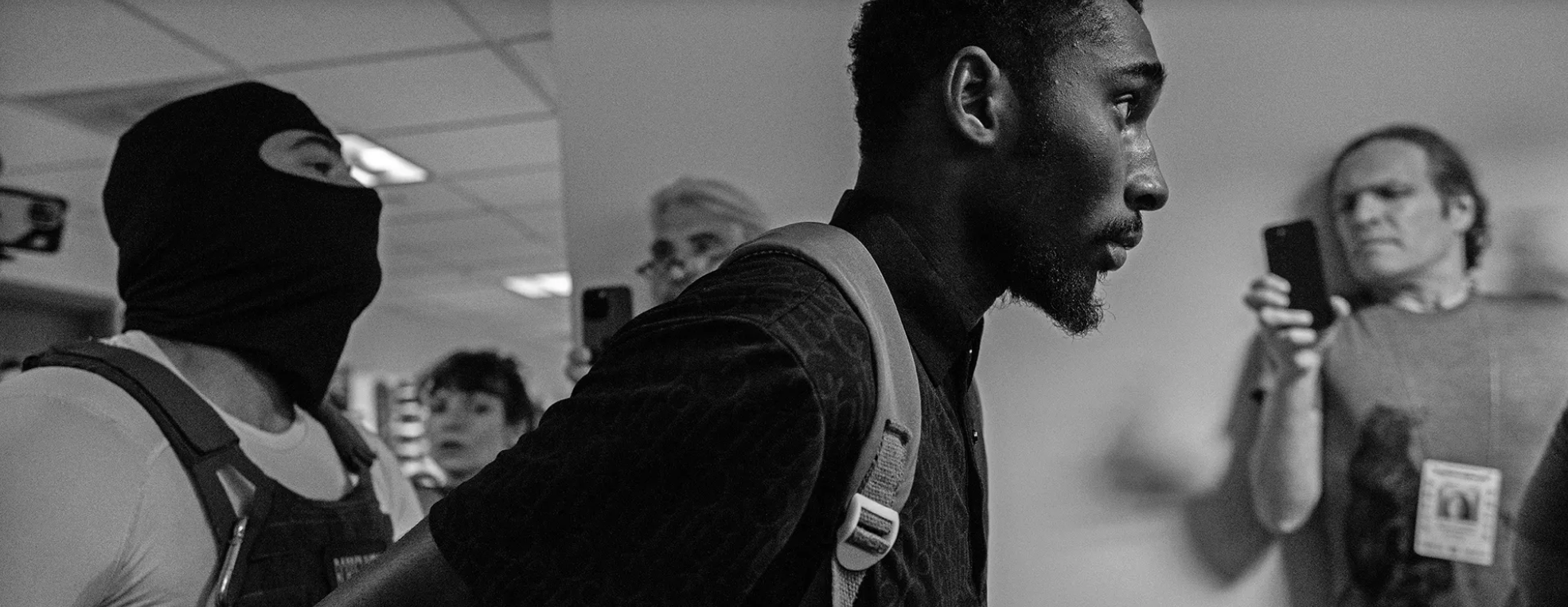A detainee is escorted down a hallway, documented by citizen volunteers. 