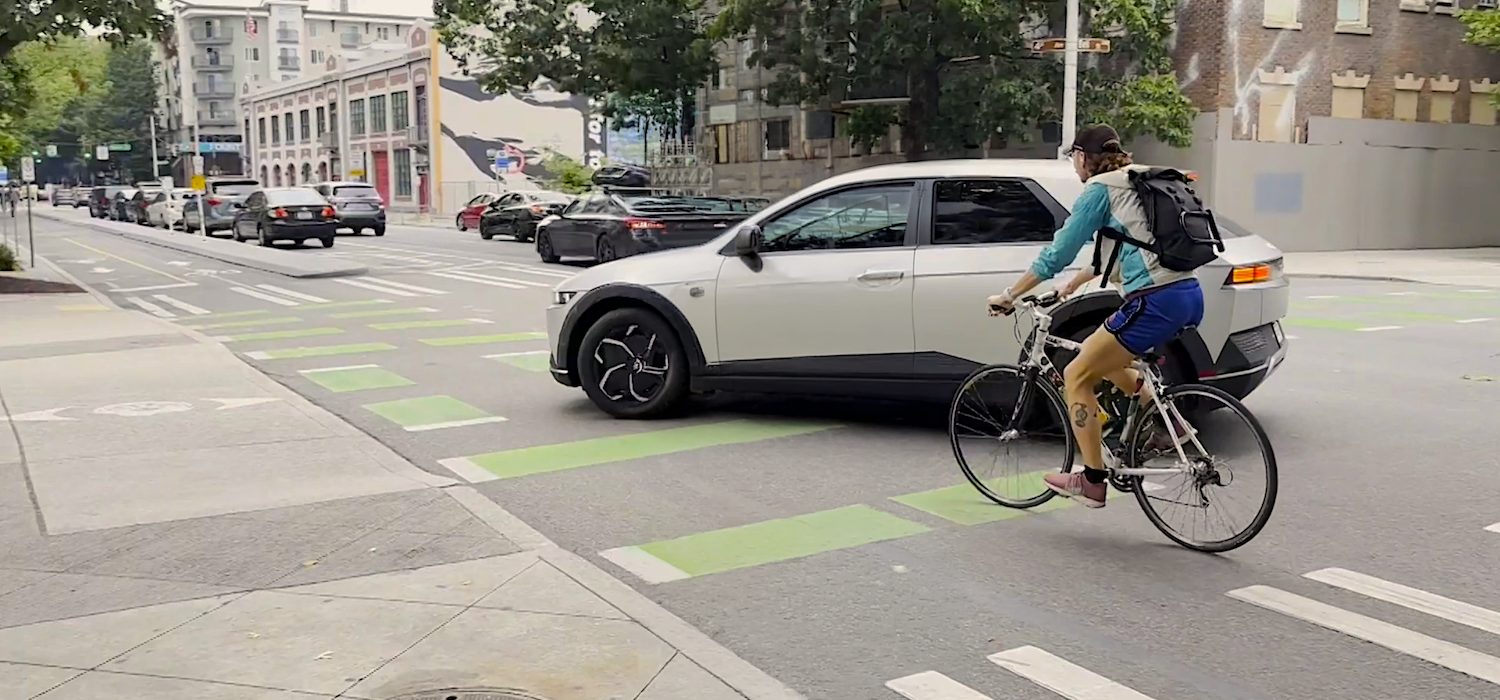 Cyclist getting cut off by a car while riding in the protected bike lane