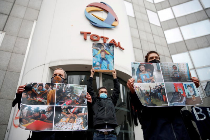 Three protestor hold up images of civilians murdered by the Myanmar military outside Total headquarters