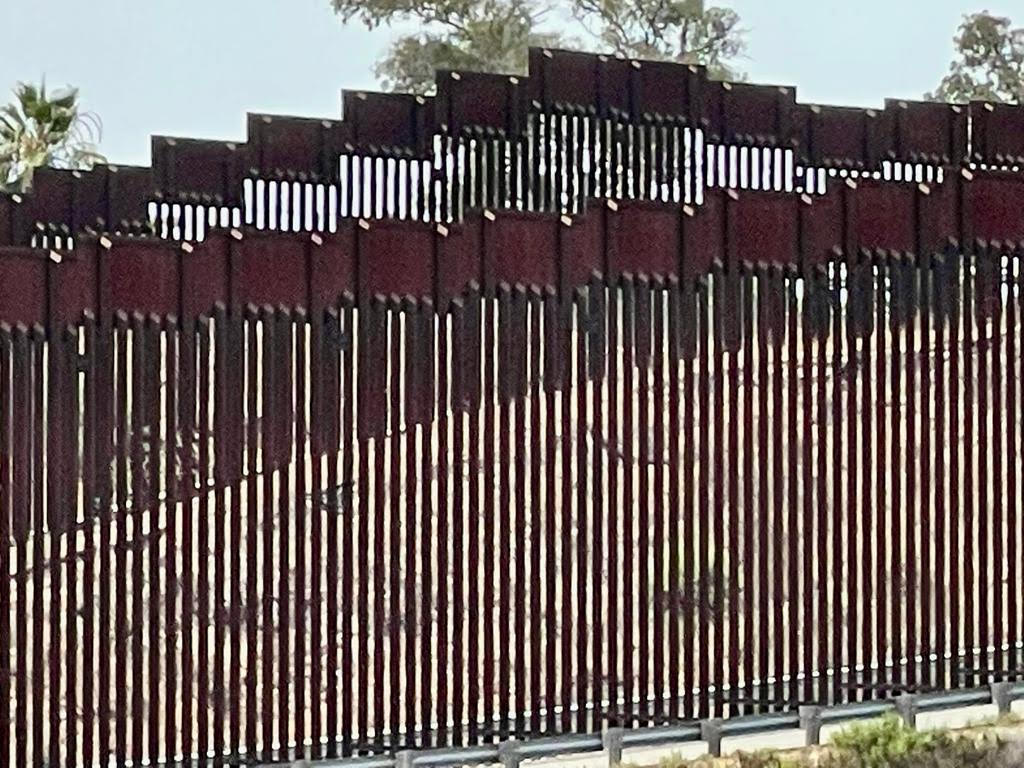 Thirty foot trump wall butting up against 18 foot existing barrier at the beginning of Friendship Park.  And Group of people on US side looking through both walls trying to greet people on the Mexican side