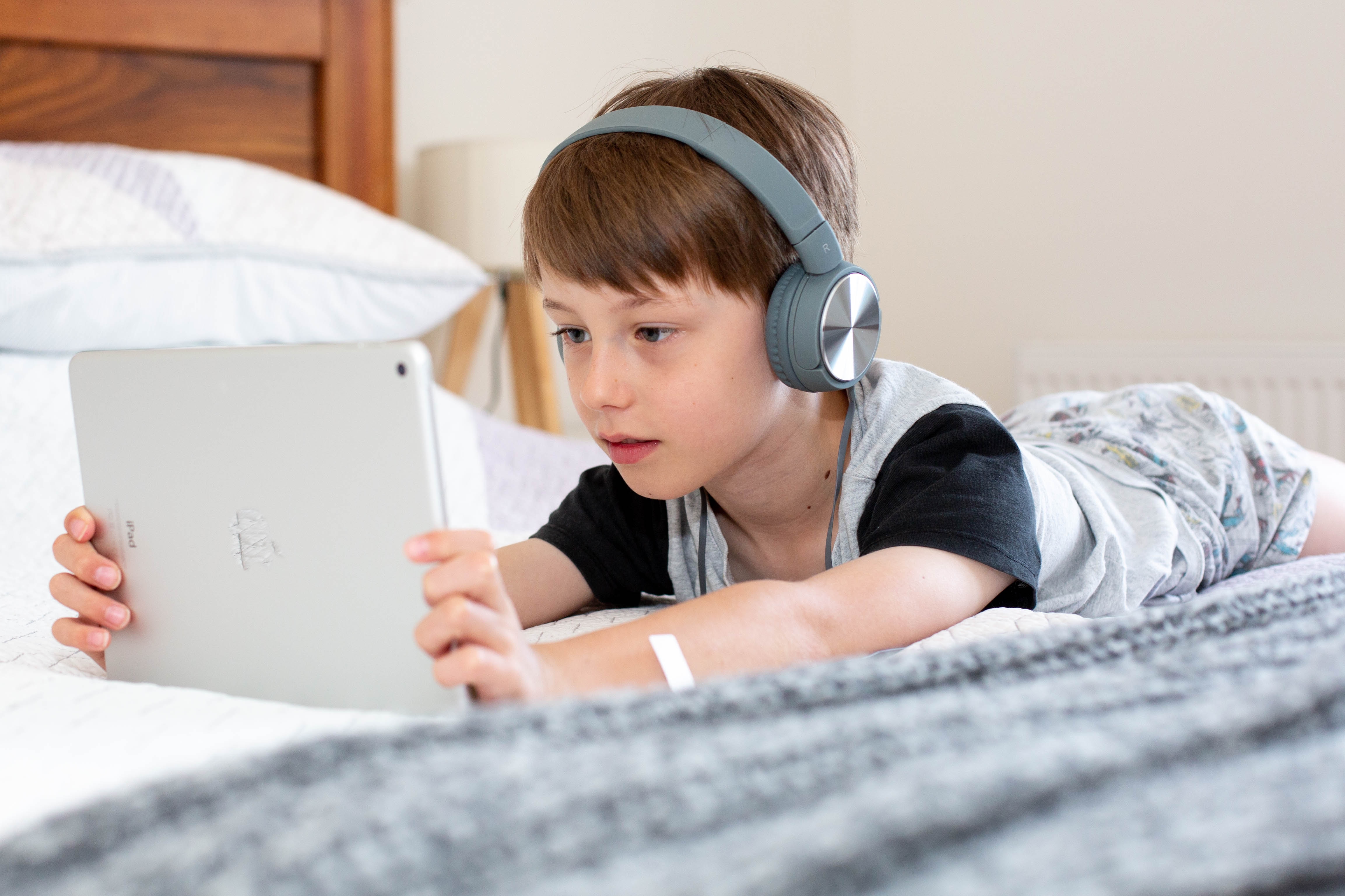 Young boy wearing headphones watches tablet.
