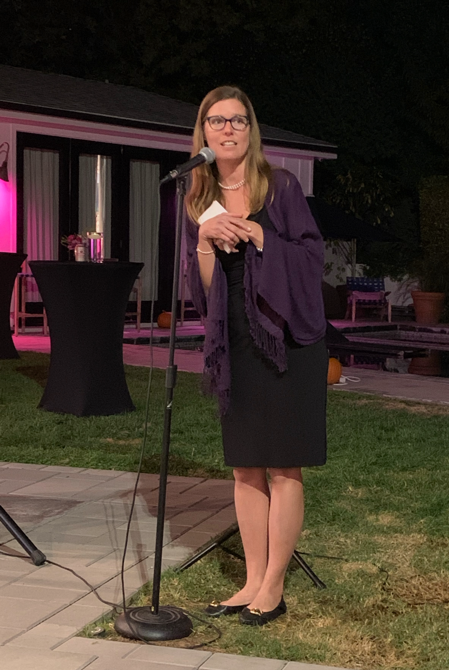 Erin Matson, a white woman in a black dress and purple shawl, speaking at an event