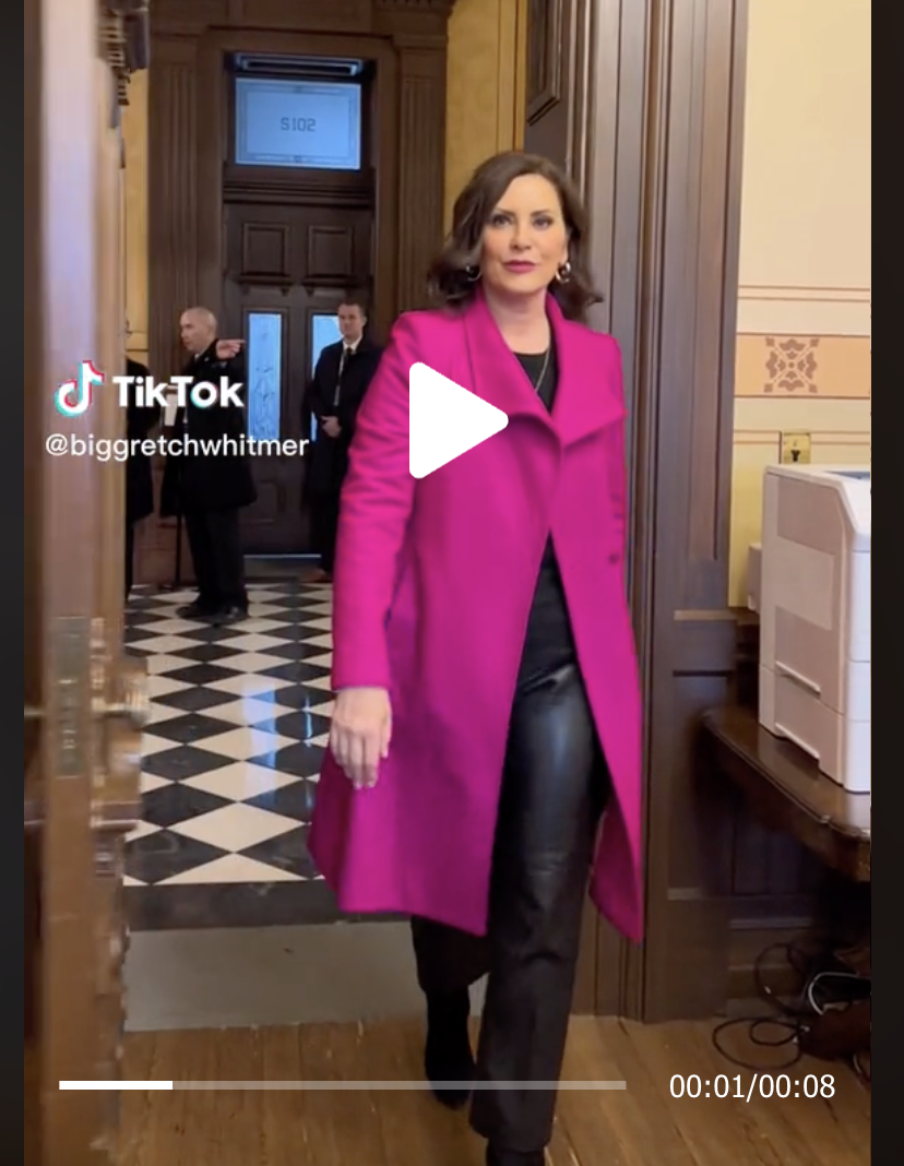 Gov Gretchen Whitmer walks into her office wearing a pink coat