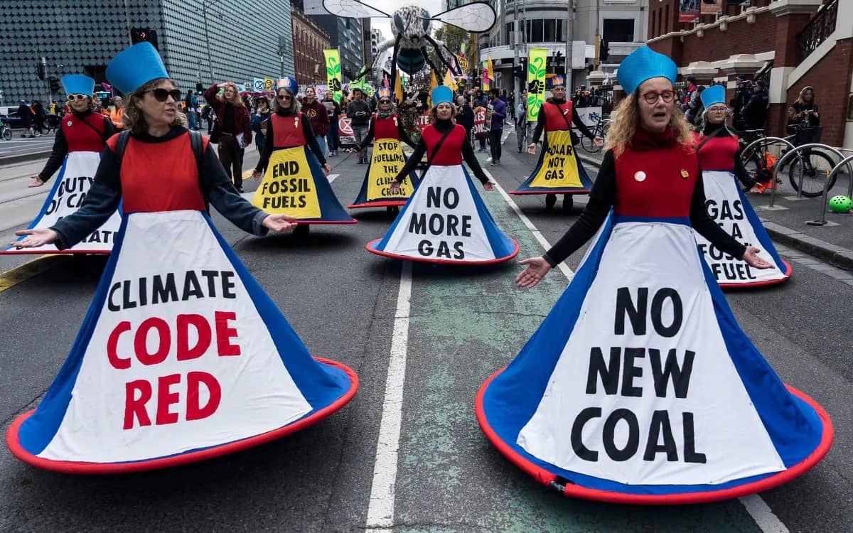 Sybils in special skirts with anti-fossil fuel messages parade down the street