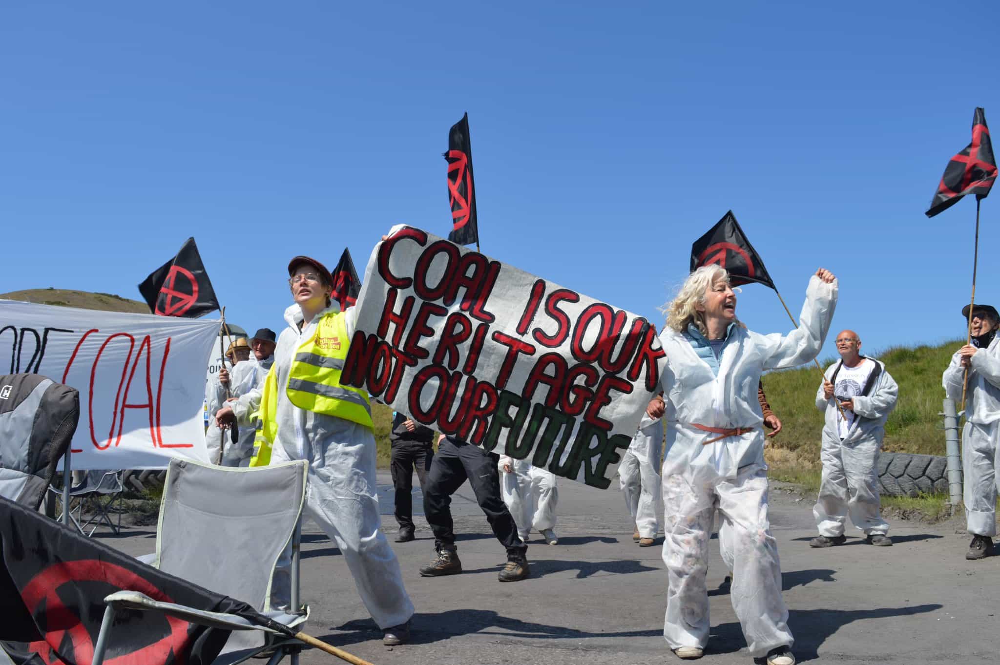 Rebels cheer outside the mine and hold a banner that says: Coal is our heritage not our future