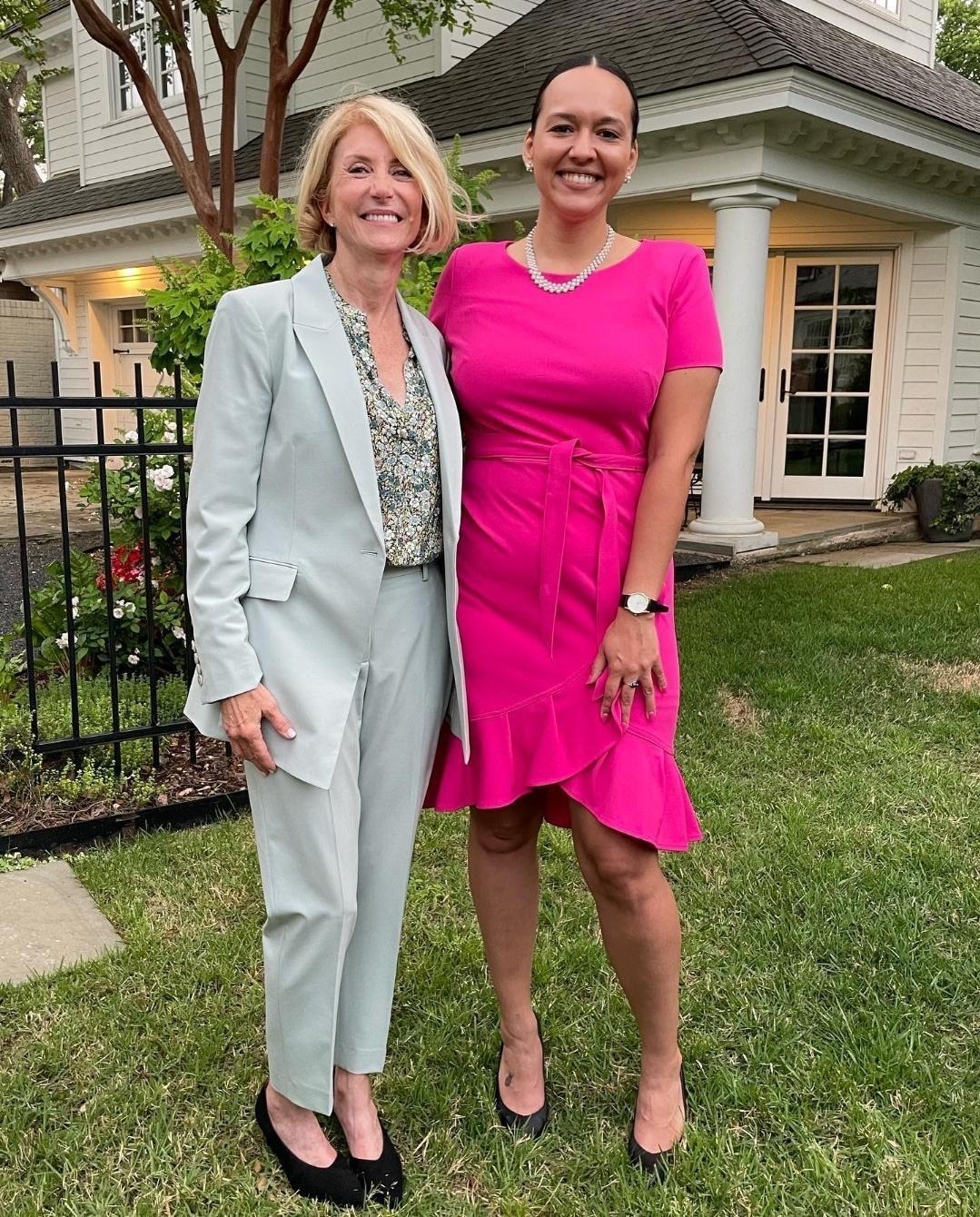 Wendy Davis in a gray pantsuit stands with her arm around Michelle Vallejo in a pink dress.