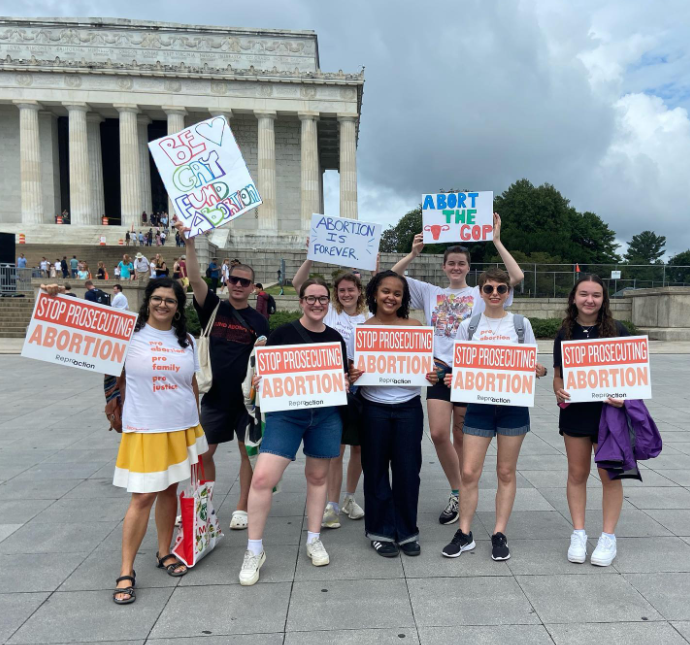 Alt-Image: A group of people stand outside SCOTUS with signs that read Stop Prosecuting Abortion, Be Gay Fund Abortion, Abortion is Forever, and Abort the GOP