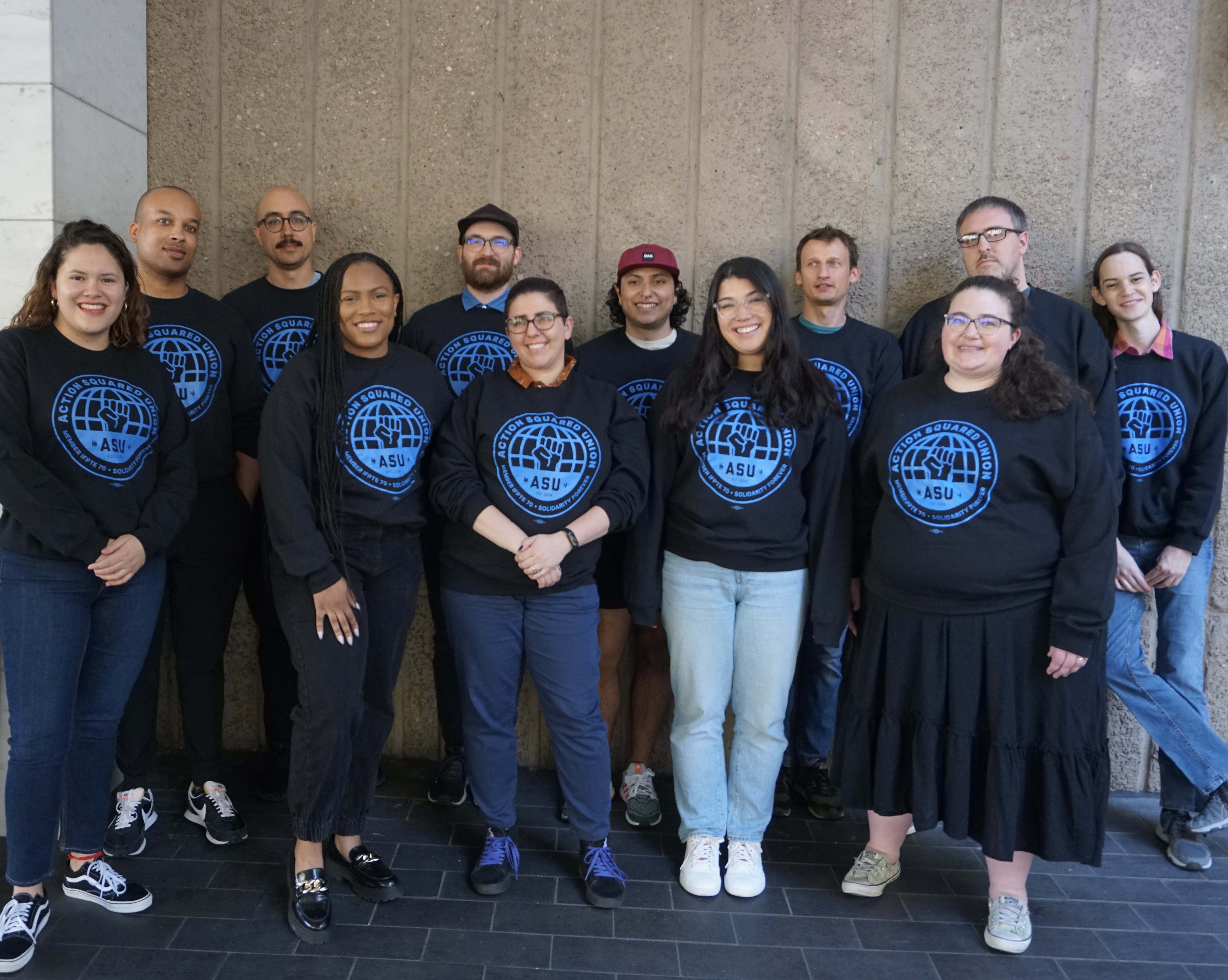 Members of the Action Network & Action Builder team posing in front of a banner that says 'Action Builder'