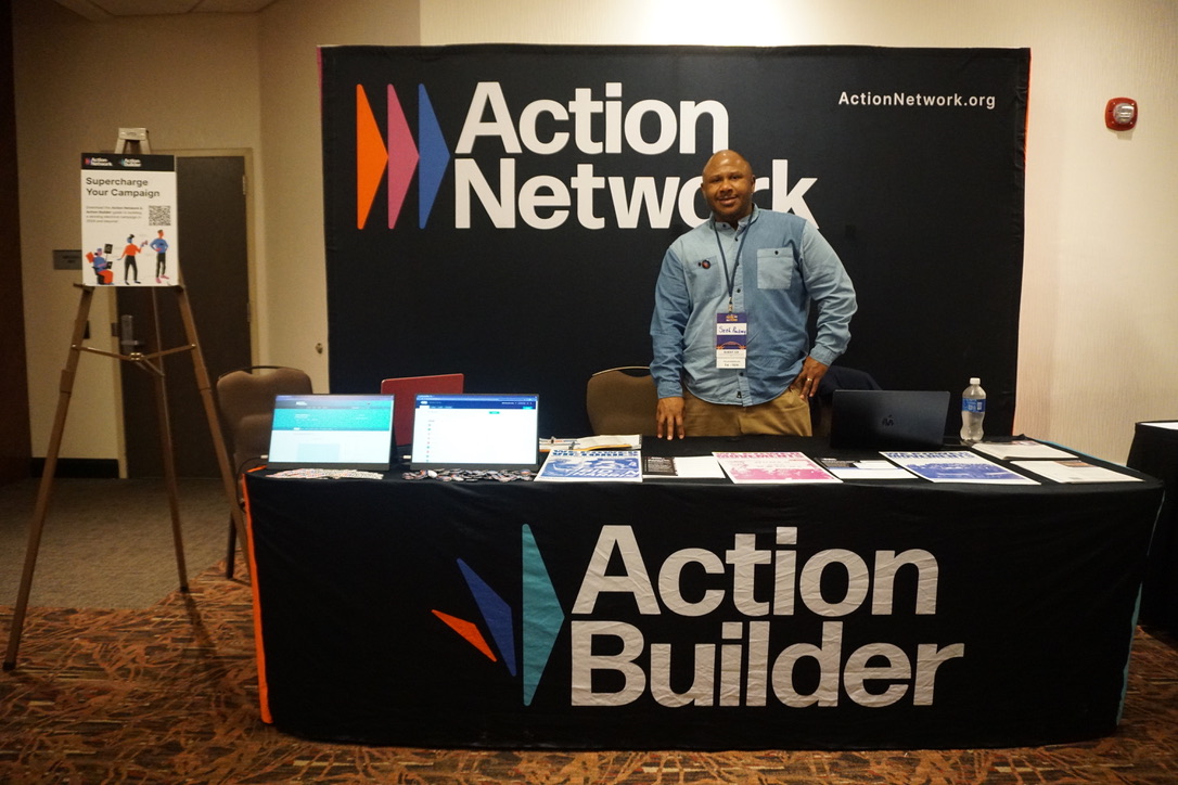 Seth Pinckney posing at the Action Network & Action Builder booth at the WisDems Convention