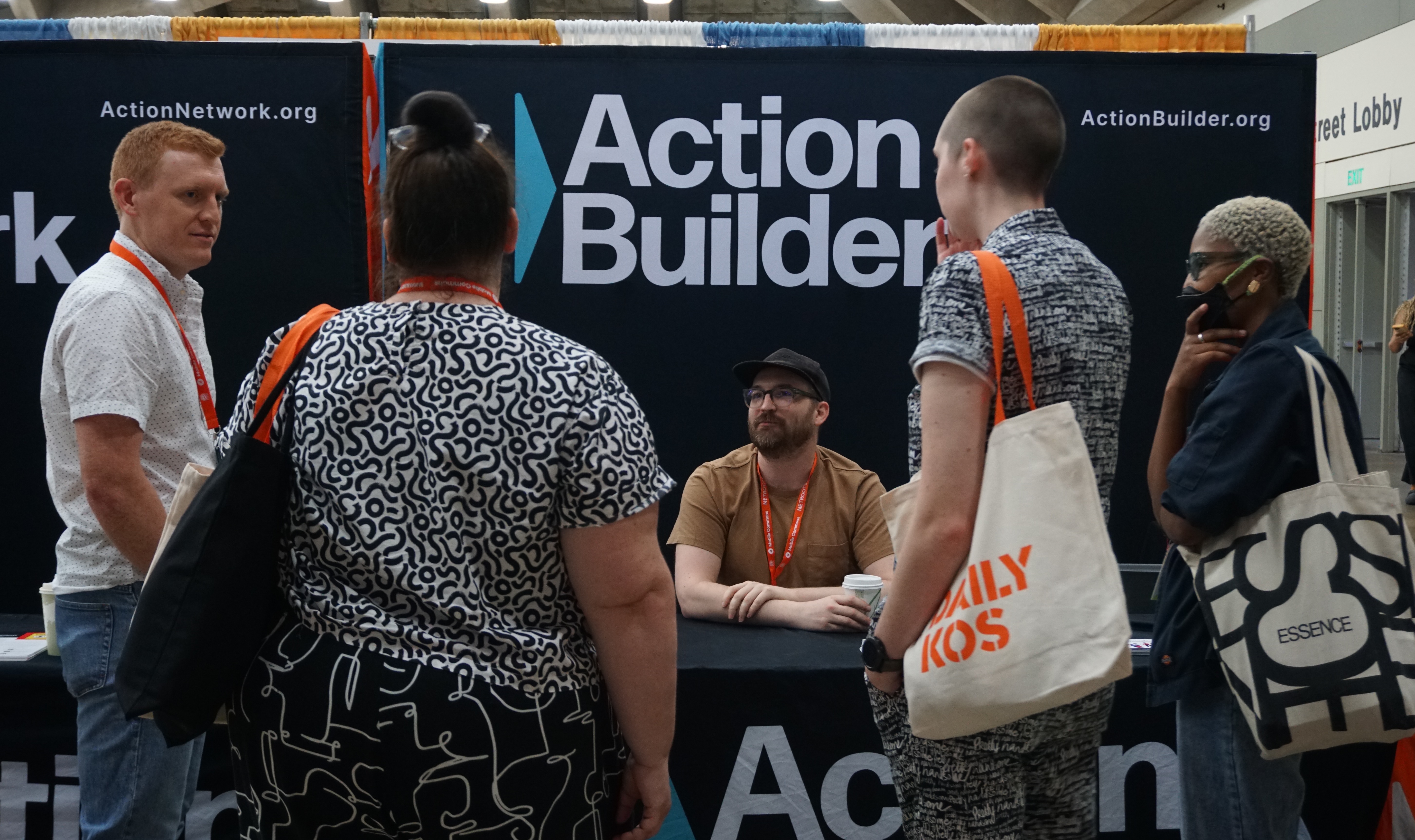 Several conference attendees standing in front of a banner that says Action Builder.