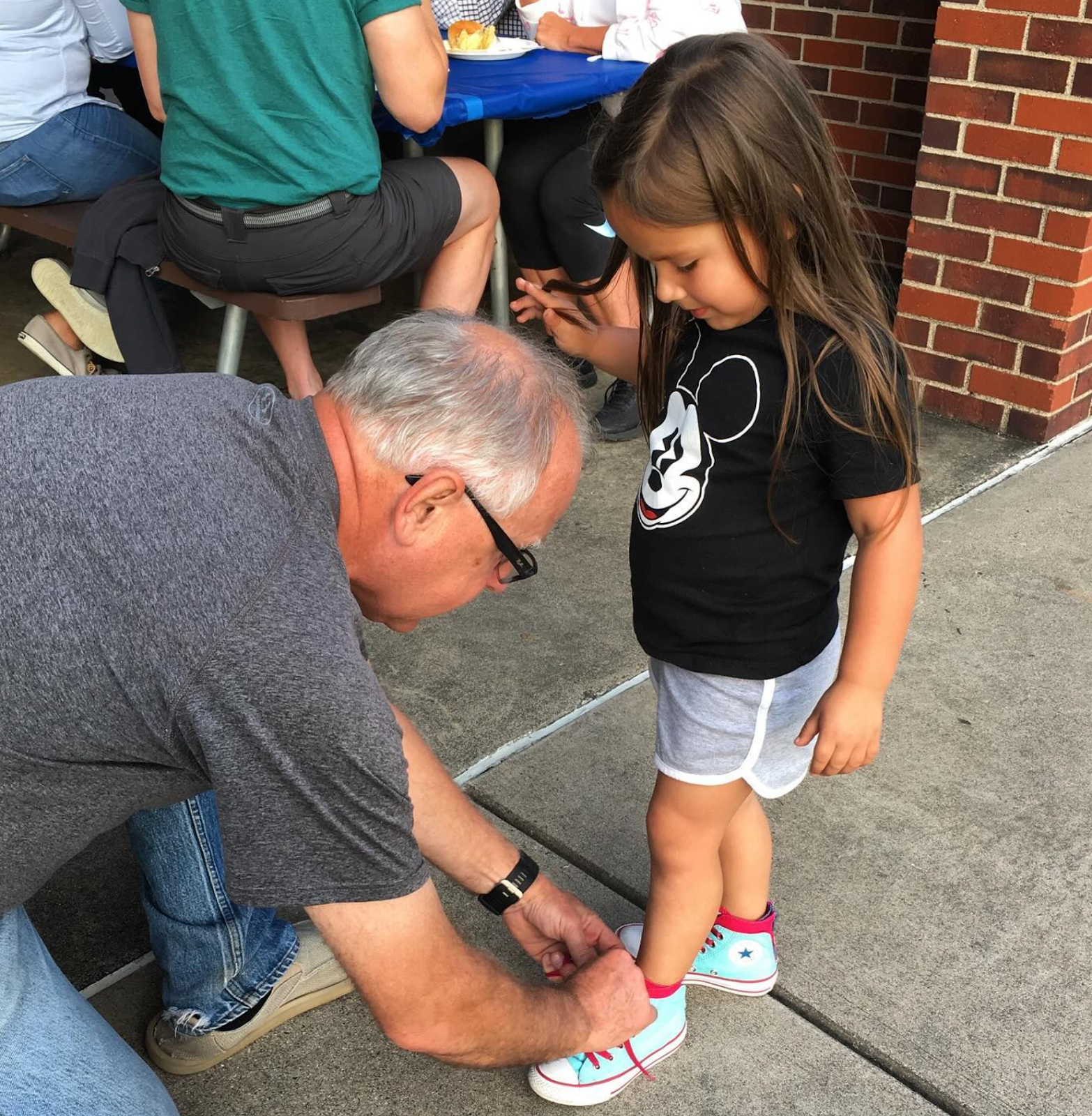 Tim Walz tying a girl's shoes