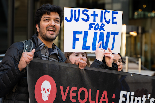 Activists protesting Veolia, one holding a sign that reading Justice for Flint