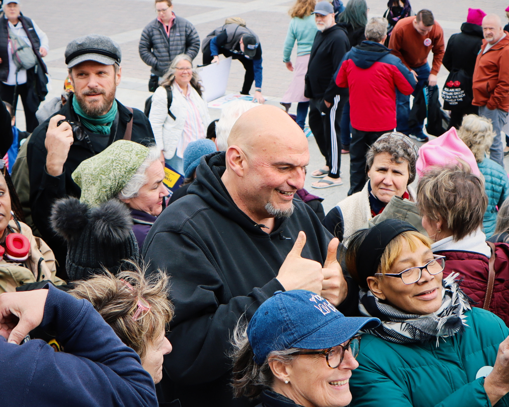 Senator John Fetterman stands in crowd talking with constituents.