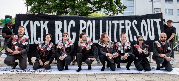 Activists in front of a sign reading Kick Big Polluters Out