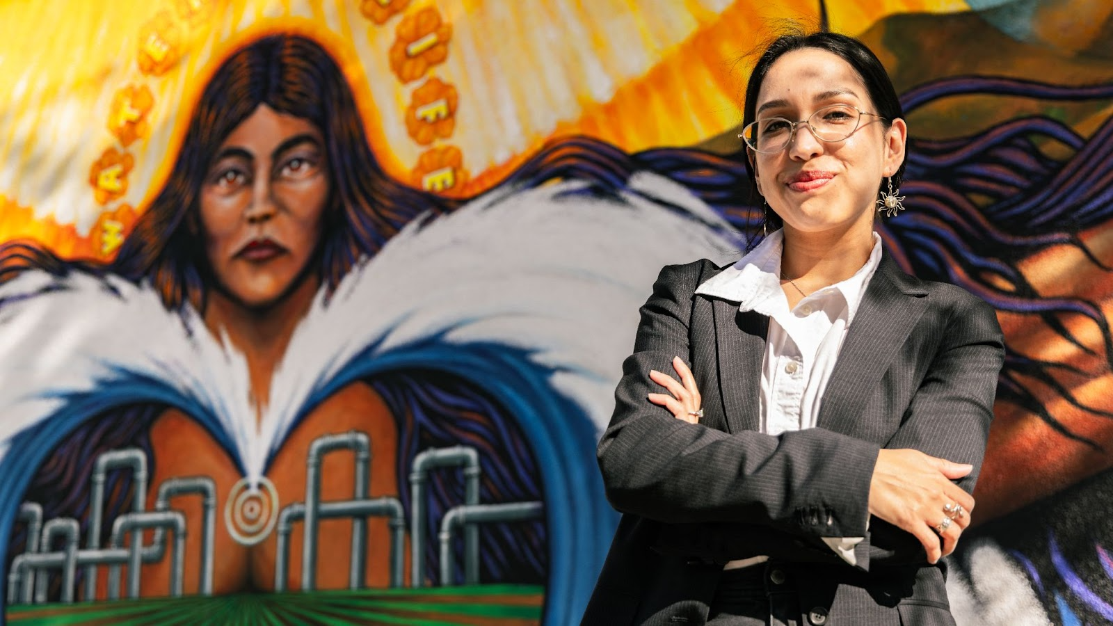 Angela stands in front of a mural 