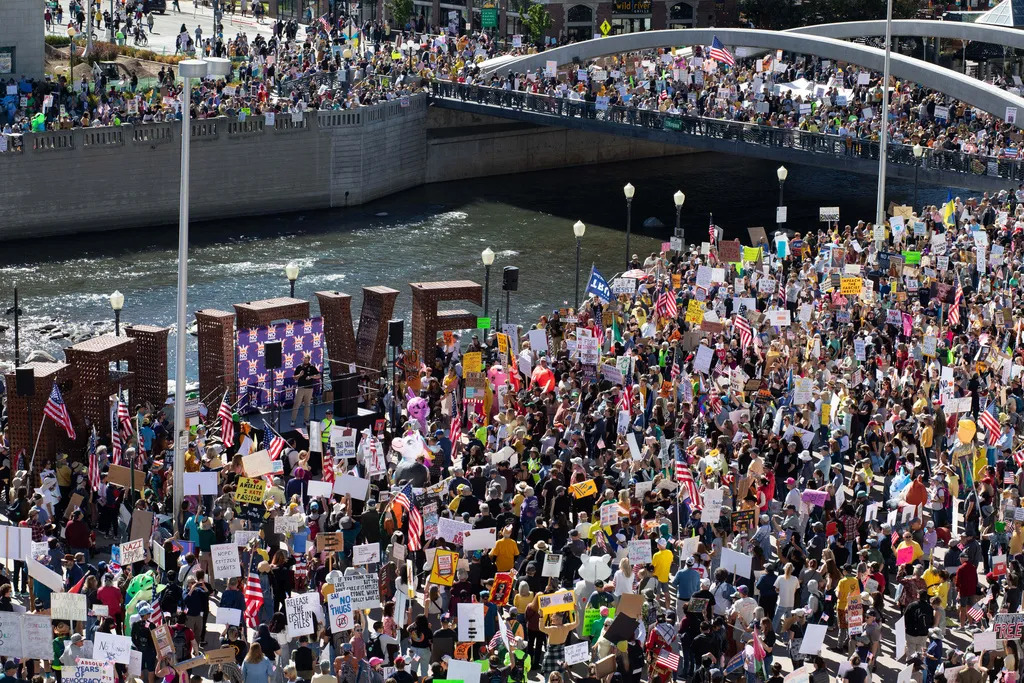 Photo of large group of protestors along a river and bridge.