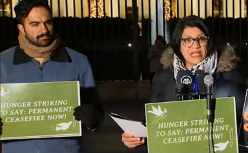 Rashida and Zohran stand outside the White House at a vigil, holding signs that say "hunger striking to say permanent ceasefire now"