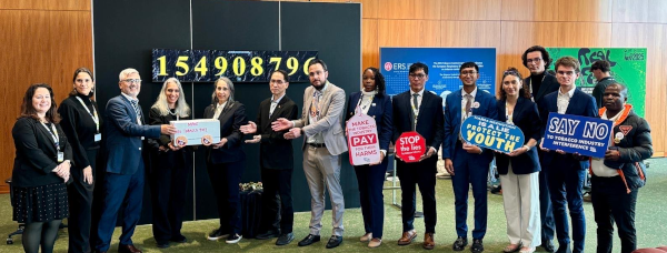A pink and orange cover of our annual report, featuring an organizing holding up a cardboard sign that says PEOPLE OVER PROFIT.