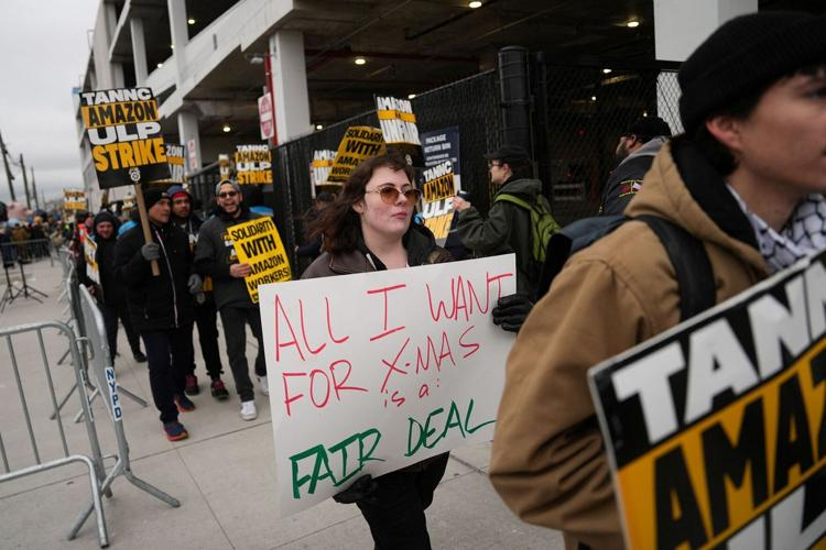 Striking Amazon workers picket. One holds the sign ALL I WANT FOR X-MAS IS A FAIR DEAL