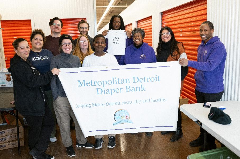 Staff at the Metropolitan Detroit Diaper Bank stand with Rashida behind a banner