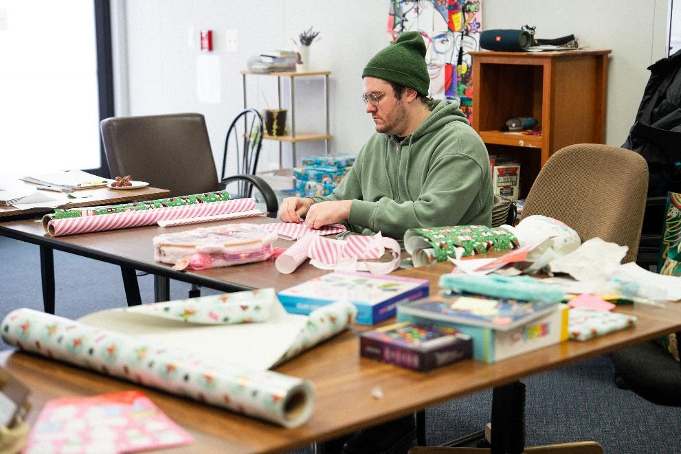 A volunteer wraps a present at a giftwrapping table A volunteer wraps a present at a giftwrapping table
