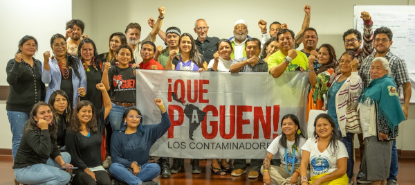 Activists holding a sign reading 'Que Paguen'