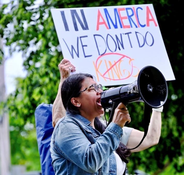 Rashida holds a bullhorn in front of a sign 