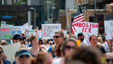 Protesters holding up signs saying Abolish ICE and other slogans.