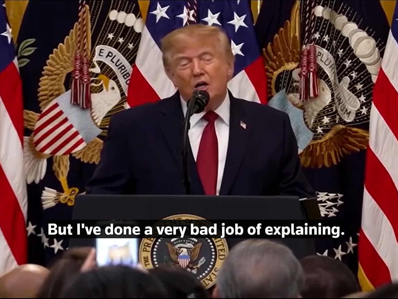 President Trump stands at a podium in front of American flags saying: But I've done a very bad job of explaining.