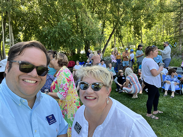 A photo of David Roth for U.S. Senate wearing a light blue button-up shirt posing next to a woman with short blonde hair at an outdoor meet and greet in Idaho