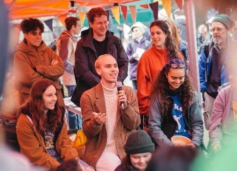 Photo showing a group of young people one is holding a microphone