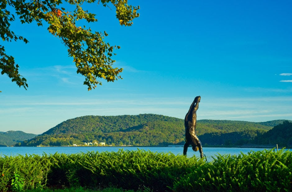 Bronze statue doing a handstand on the banks of the Hudson River